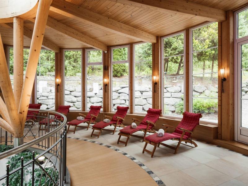 Gemütlicher Ruheraum mit roten Liegestühlen und großer Fensterfront zu einem Garten.