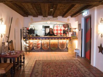 Coin réception rustique avec plafond à poutres en bois, sol recouvert de tapis et comptoir décoratif.