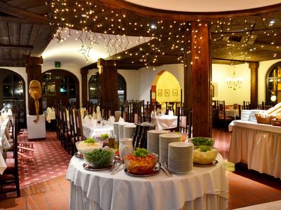 Eleganter Speisesaal mit dekorierten Tischen, warmem Licht und Buffet im Zentrum.
