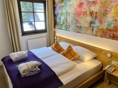 Chambre d'hôtel moderne avec lit double, décoration murale colorée et serviettes sur le lit.