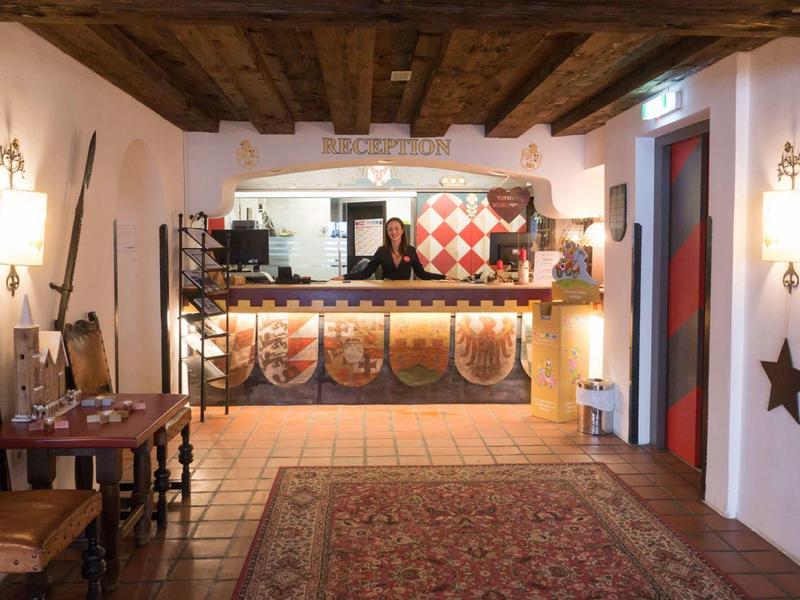 Rustikales Zimmer mit Holzdecke, Schilden an der Bar, Teppichboden und antiken Möbeln.