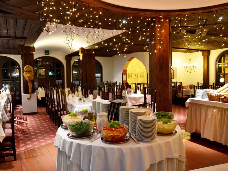 Eleganter Speisesaal mit dekorierten Tischen, warmem Licht und Buffet im Zentrum.