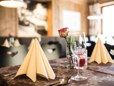 Eleganter gedeckter Tisch mit gefalteten Servietten und einer roten Rose in einem Glas im Restaurant.