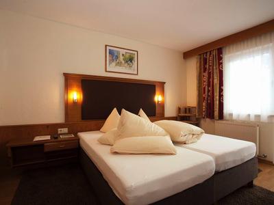 Gemütliches Hotelzimmer mit zwei Einzelbetten, Kissen und warmem Licht.