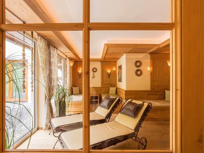 Blick durch Fenster auf einen gemütlichen Ruheraum mit Liegestühlen und warmem Holzdekor.