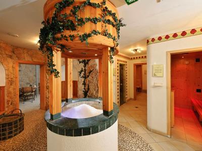 Interno di un'area benessere con una fontana, piante e accesso alla sauna.