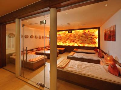 Sala relax accogliente con comodi lettini e illuminazione calda con accenti in legno.