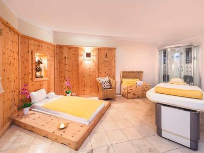 Luminoso centro benessere con pareti in legno, lettino da massaggio e cuscini decorativi.