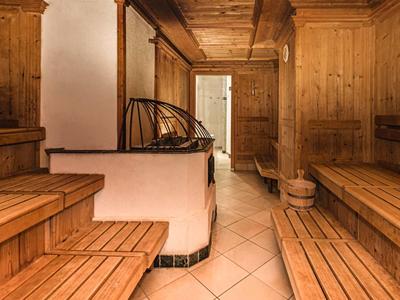 Accogliente sauna in legno con panche e stufa piastrellata con luce calda