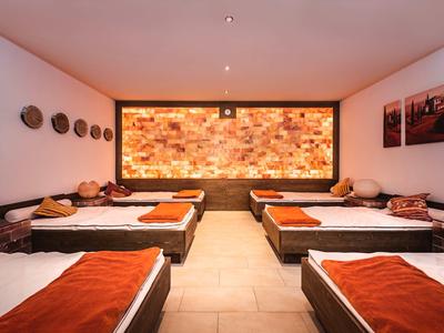 Interno di una sala relax spa con sei letti da massaggio e illuminazione calda.