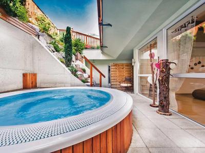 Vasca idromassaggio moderna sulla terrazza con parete di vetro e vista montagna sullo sfondo