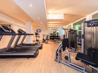 Palestra moderna con tapis roulant, attrezzature per allenamento e pavimento in legno.