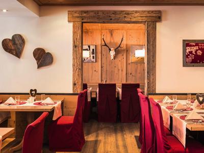 Accogliente sala da pranzo rustica con tavoli in legno e sedie rosse in un hotel.