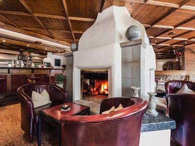 Area lounge accogliente in hotel con poltrone in pelle e camino in ambiente rustico.