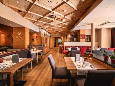 Accogliente sala da pranzo dell'hotel con pavimento in legno, sedute moderne e soffitto in legno.