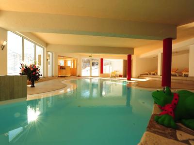 Piscina interna in hotel con grandi finestre e un'atmosfera accogliente.
