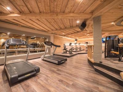 Gimnasio moderno con cintas de correr y máquinas de remo en un entorno con techo de madera.