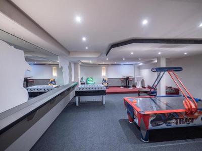 Ein heller, moderner Raum mit Airhockey- und Kickertisch, grauem Teppich und weißen Wänden.