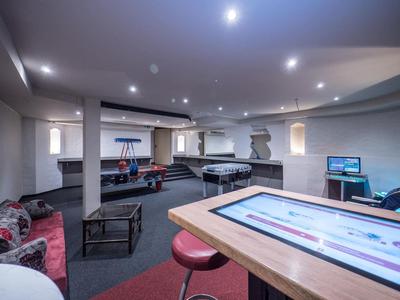 Moderner Freizeitraum mit Billardtisch, Sitzecken, Hockern und konzentrischer Deckenbeleuchtung.