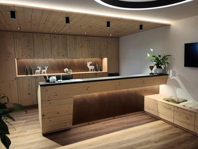 Recepción de hotel moderna con paneles de madera, iluminación elegante y detalles de plantas.