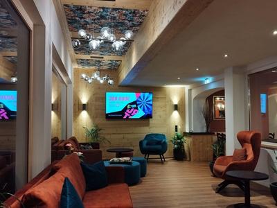 Moderner Wartebereich mit braunen Ledersesseln, Holzbalken und spiegelnder Decke.