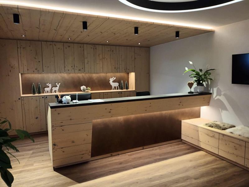 Moderner Empfangsbereich mit Holzvertäfelung, Beleuchtung, Dekofiguren und Pflanzen.