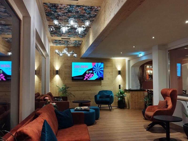 Moderner Wartebereich mit braunen Ledersesseln, Holzbalken und spiegelnder Decke.