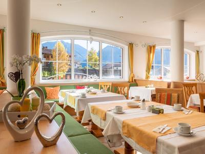 Světla restaurace se slavnostně prostřenými stoly a výhledem na hory skrz velká okna.