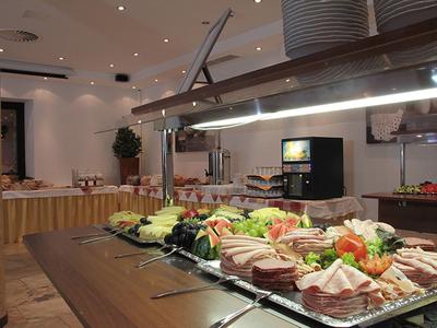 Buffet mit verschiedenen Wurst- und Fleischsorten, dekoriert mit Salat und Gemüse in einem Raum.