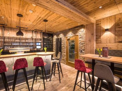 Bar acogedor con interior de madera y taburetes rojos en un hotel.