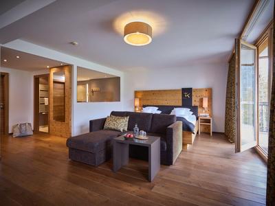 Modern eingerichtetes Hotelzimmer mit Bett, Sofa und großer Fensterfront.