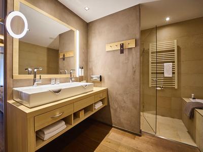 Modernes Badezimmer mit Doppelwaschbecken, großer Spiegel und begehbarer Dusche in warmen Farbtönen.