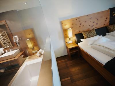Modernes Hotelzimmer mit gemütlichem Bett, Nachttischen und beleuchtetem Waschbereich.
