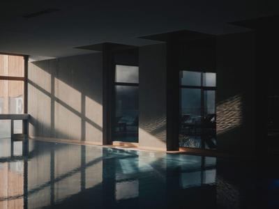 Innenbereich eines Hotels mit Swimmingpool und Tageslicht, das Schatten auf die Wände wirft.
