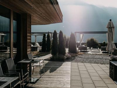 Moderne Terrasse mit Stühlen, Tischen und Blick auf Berge im Hintergrund an einem sonnigen Tag.