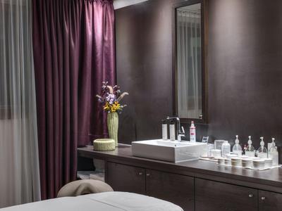 Modernes Badezimmer mit Waschbecken, Spiegel, lilafarbenen Vorhängen und Blumenarrangement.