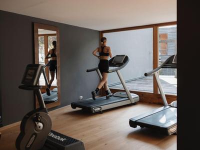 Moderner Fitnessraum mit Laufbändern und Spinningrad, große Fenster mit Aussicht.