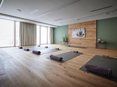 Heller, geräumiger Yoga-Raum mit Holzboden, Matten und ruhiger Atmosphäre in einem Hotel.