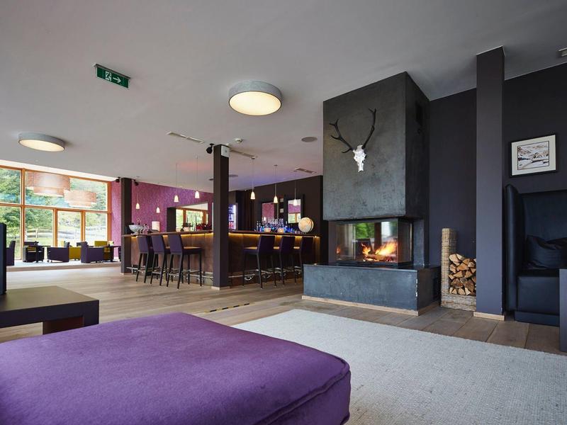Moderner Hotel-Lobby mit violettem Sitz, Kamin, Holztresen und großem Fenster.