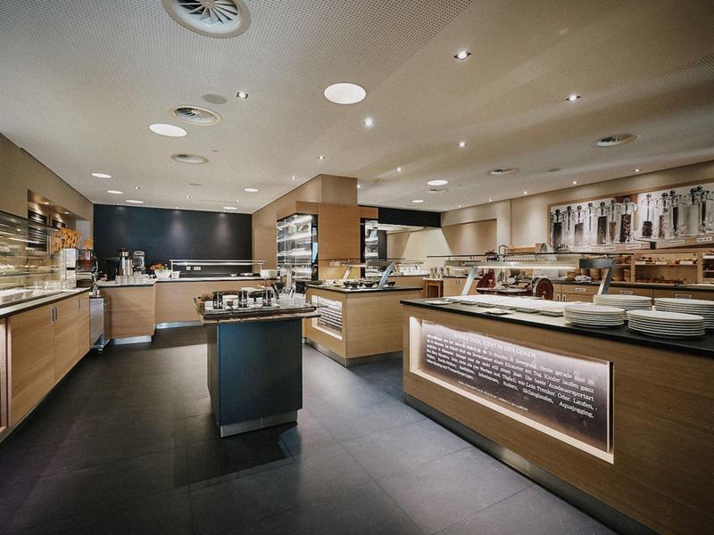 Moderne Metzgerei mit Holztheken, Vitrinen voller Fleischwaren und hellem Deckenlicht.