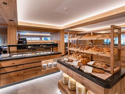 Modernes Hotelbuffet mit Brotangebot und Holzregalen in warmem Licht.