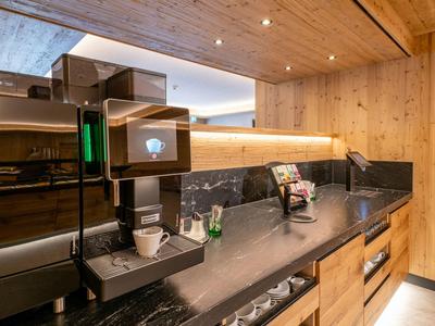 Moderne Hotelküche mit Kaffeefach, Holzverkleidung und schwarzer Arbeitsfläche.