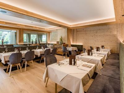 Modernes Hotelrestaurant mit gedeckten Tischen, bequemen Stühlen und warmem Holzdekor.
