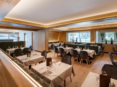 Moderner Hotelrestaurantbereich mit gedeckten Tischen, Holzverkleidung und großem Fenster.