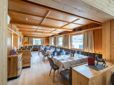 Helles Restaurant mit Holzwänden und Decke, gedeckten Tischen und gepolsterten Stühlen.
