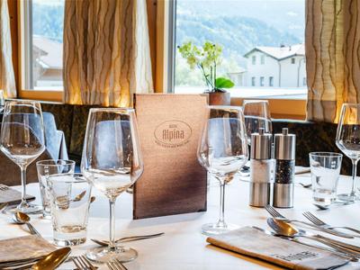 Eleganter gedeckter Tisch mit Gläsern und Menükarten in einem Restaurant mit Fensterblick auf Berge.