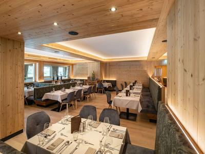 Modernes Restaurant mit Holzmöbeln, weißen Tischdecken und gedämmtem Licht.