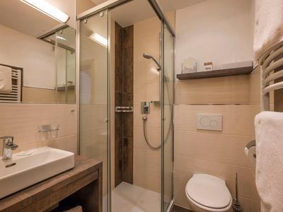 Kompaktes Badezimmer mit Dusche, Waschbecken und WC in warmen, beigen Farbtönen.