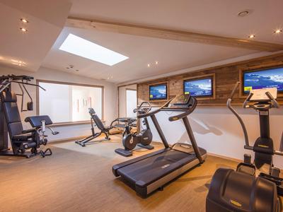 Modernes Fitnessstudio mit Trainingsgeräten und natürlichem Licht durch Dachfenster im Hotel.