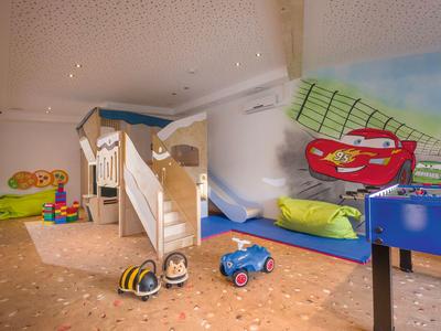Kinderspielzimmer mit Etagenbett, Spielzeugautos und bunten Wandmotiven im Hotel.